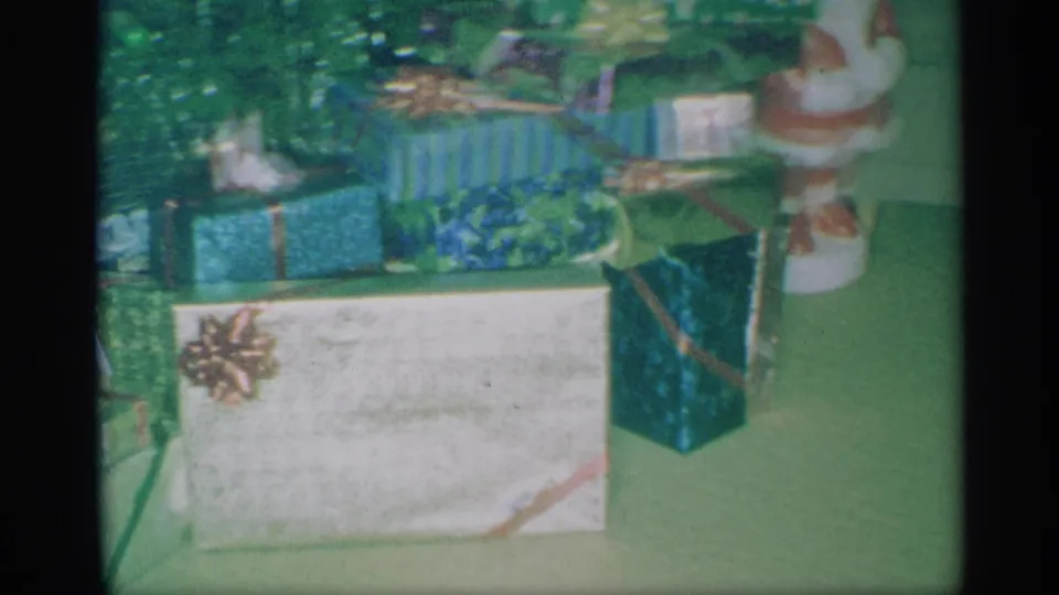A close 1959 home-movie view shows wrapped presents, bows and a Santa figurine near the Christmas tree.