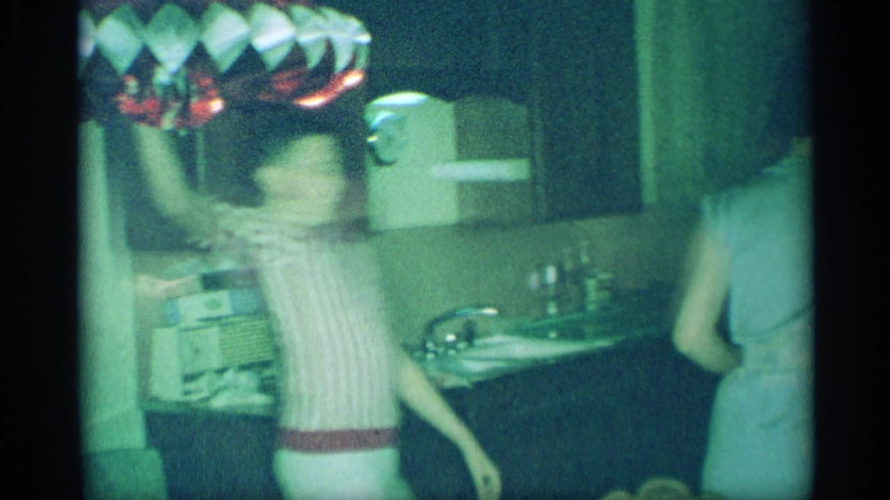 1959 New York home-movie frame showing a blurred woman moving through the kitchen near the counter and sink.