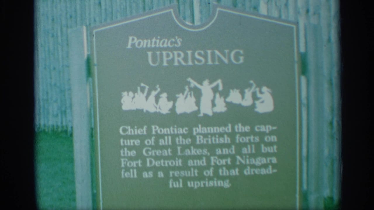 The 8mm frame holds on the Pontiac's Uprising marker, showing the green sign, white title, silhouette figures, and partially legible historical text.