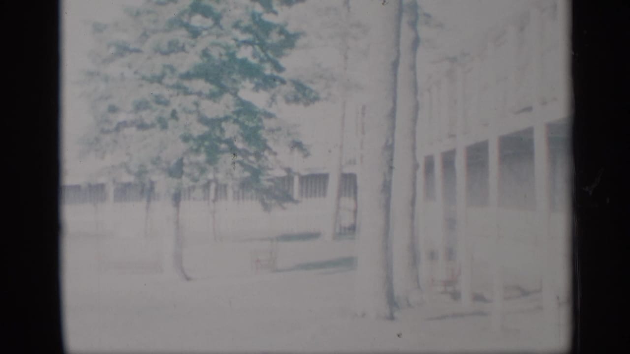 Low building and trees seen through a faded 8mm contact-sheet frame.
