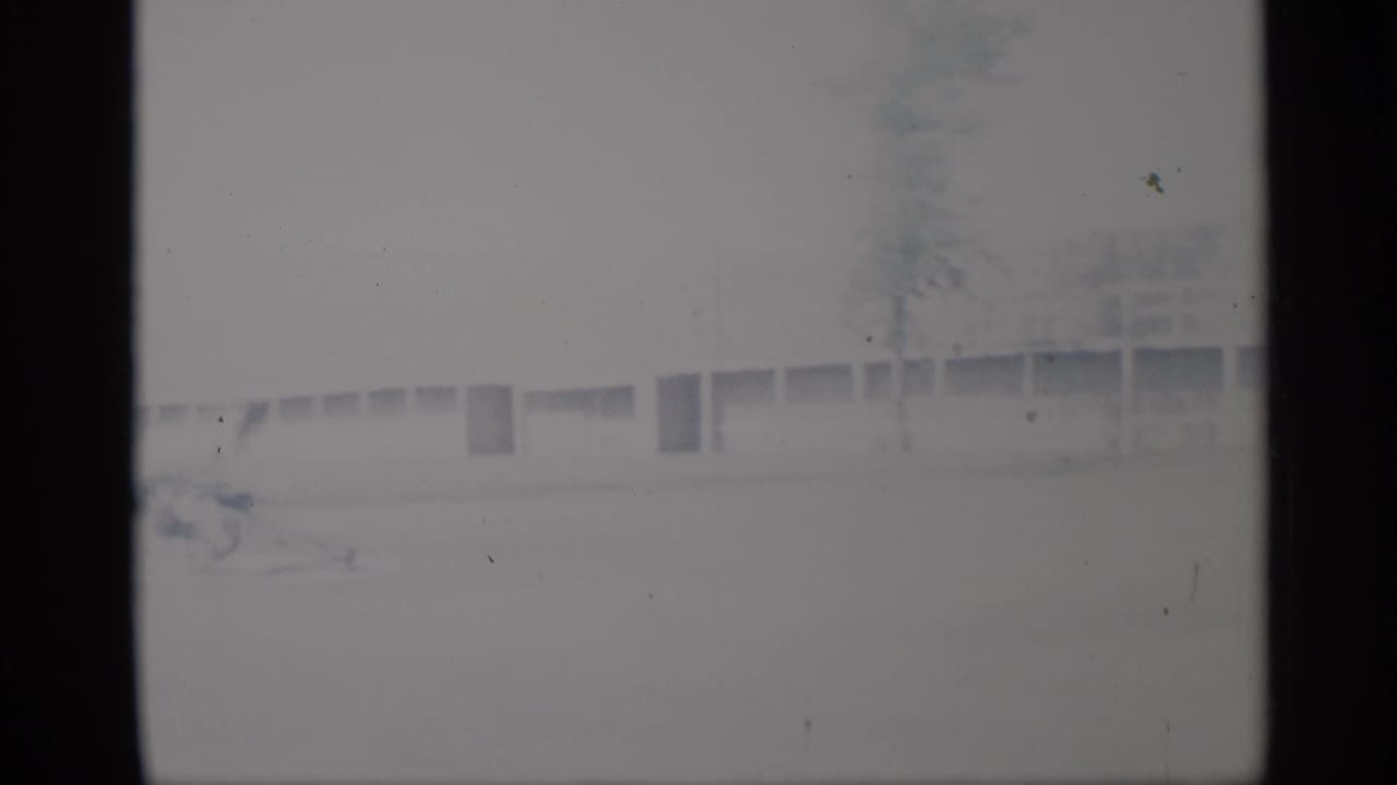 Very pale 1959 New York 8mm frame showing a low exterior building, trees, and dark contact-sheet borders.