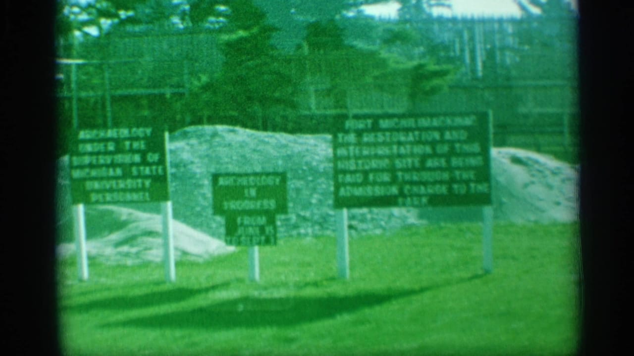 Visitor-shot 8mm frame of Fort Michilimackinac signage describing archaeology, restoration, and admission-supported work.