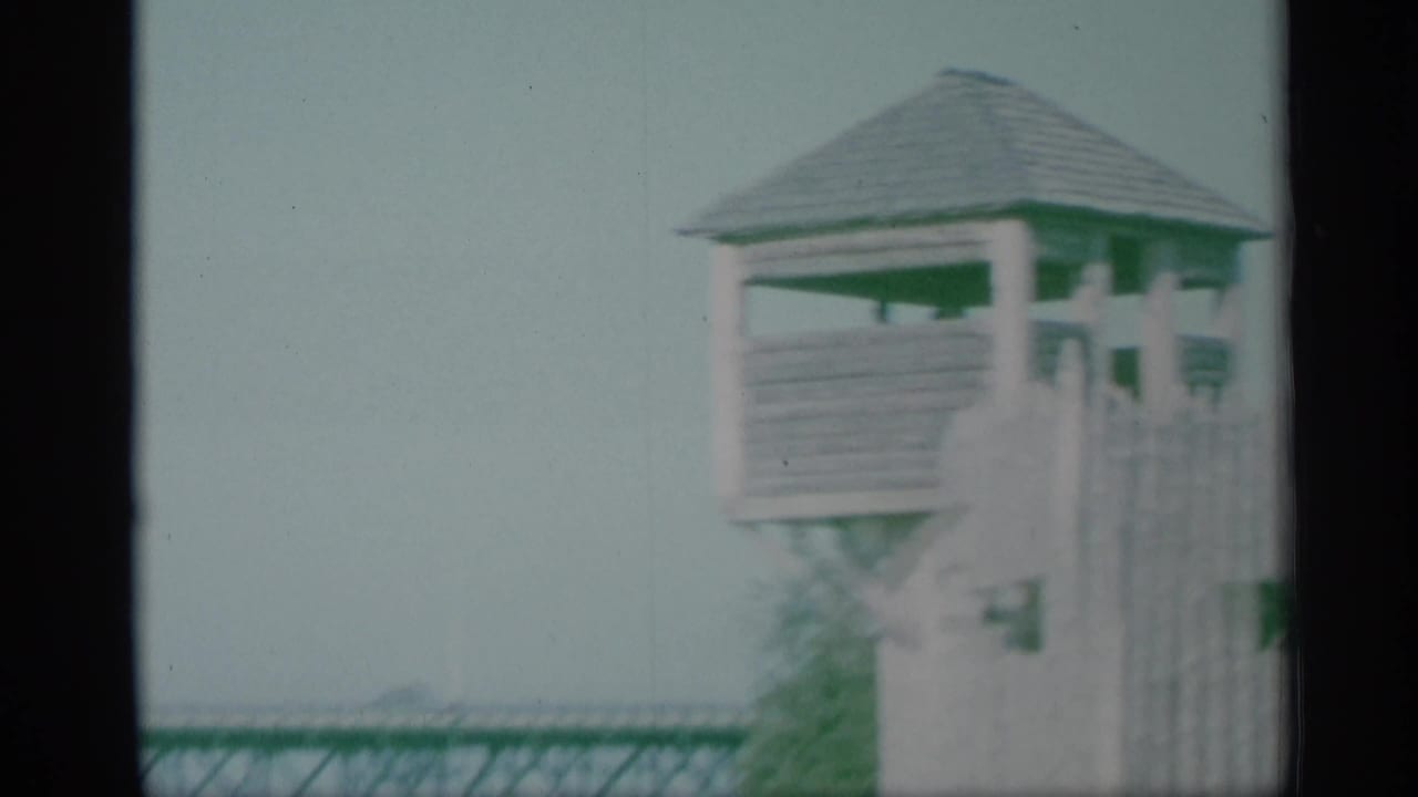 Soft 8mm frame of a wooden lookout tower near a New York waterfront, with part of a truss bridge in the background.