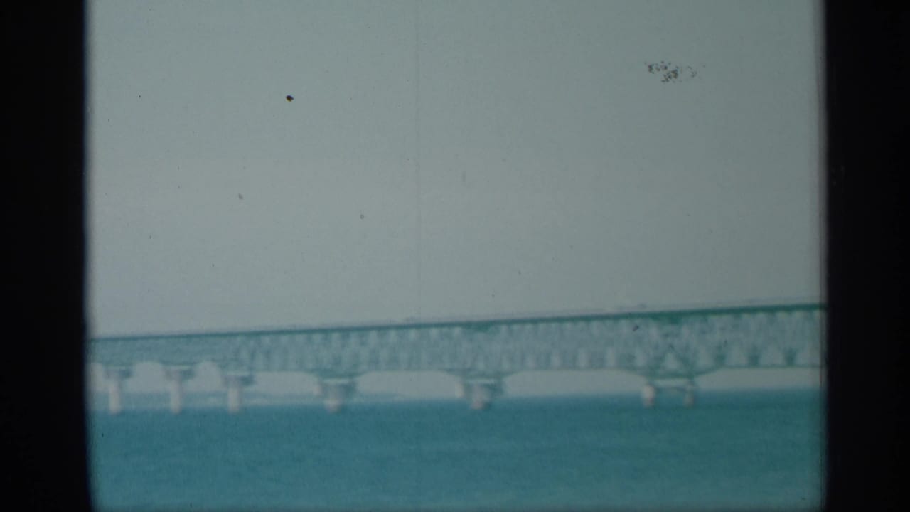 Distant bridge span across blue-green water under a pale sky.
