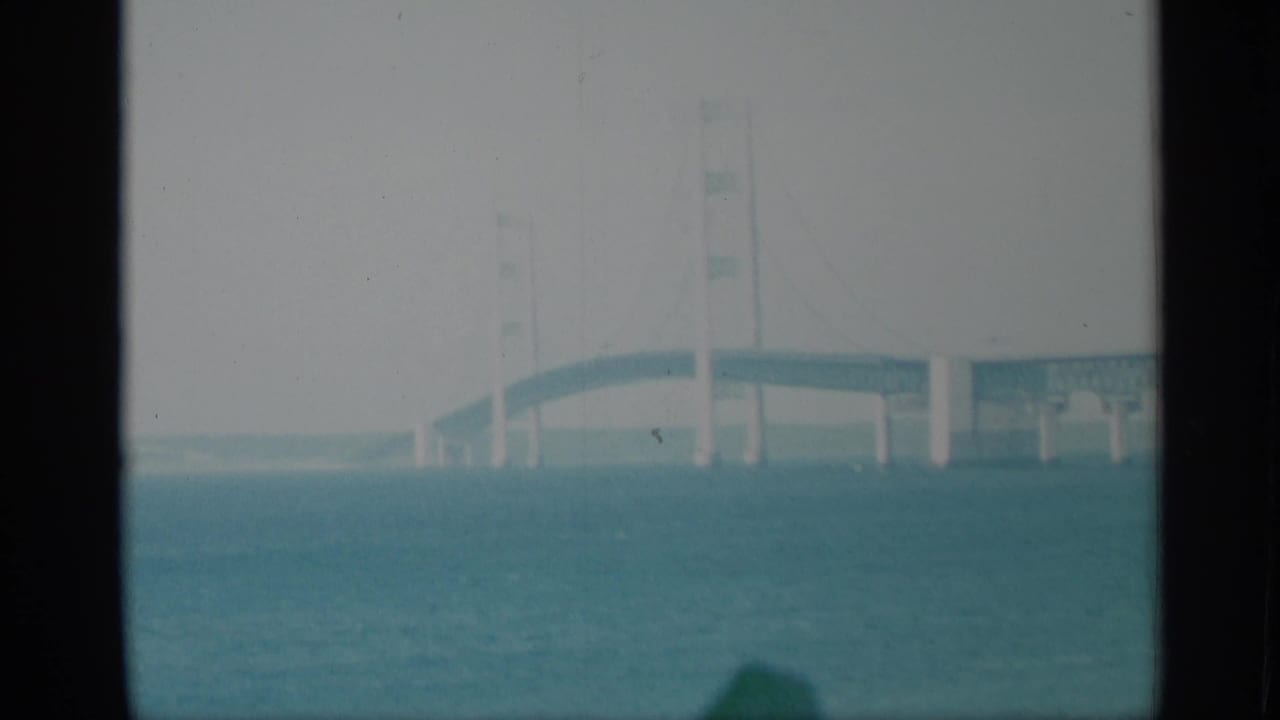 1959 New York 8mm frame with a pale bridge section over blue-green water, partly obscured by dark foreground divisions.