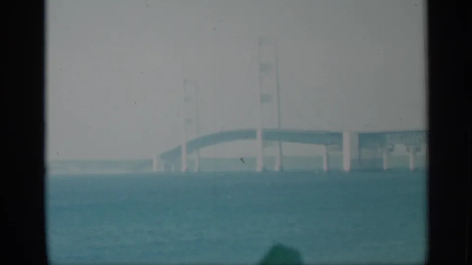 1959 New York 8mm frame with a pale bridge section over blue-green water, partly obscured by dark foreground divisions.