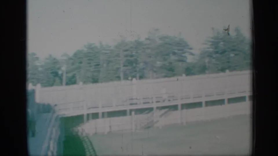 1959 New York 8mm frame showing a raised walkway and railings at a historic fort-like site, with trees beyond and soft aged-film color.