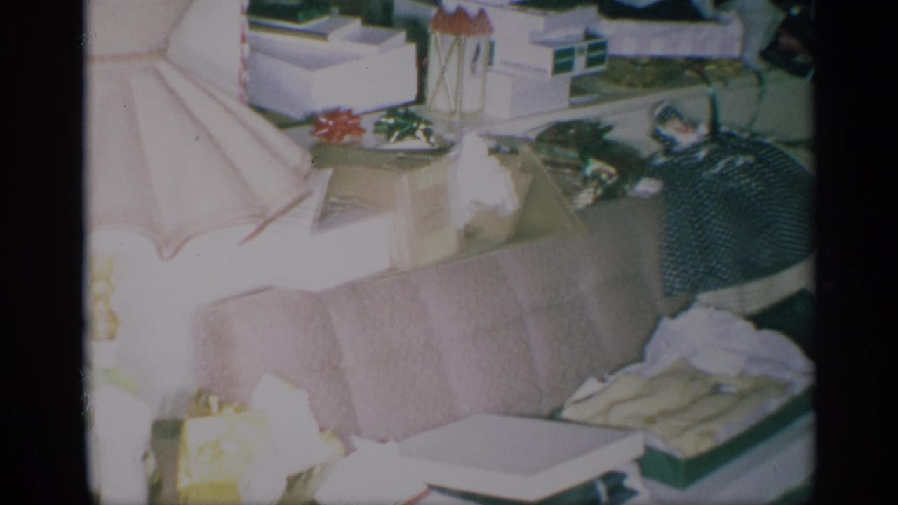 Cluttered living area with sofa, boxes, papers, and household items near a kitchen edge.