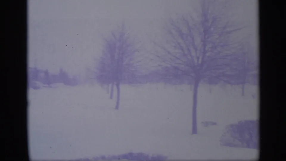 1959 New York 8mm frame showing a snow-covered residential landscape with leafless trees and distant houses.