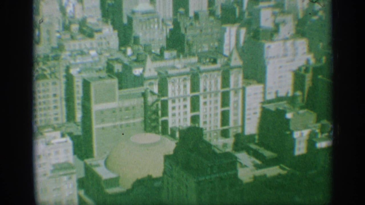 1959 New York 8mm frame looking down over dense buildings and a pale domed roof in bright sun.