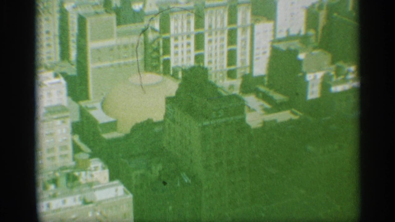 1959 New York 8mm frame showing a downward view of tall buildings, rooftops, and the domed structure.