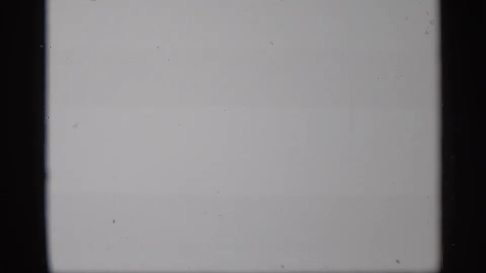 Overexposed or leader-like 8mm frame from the 1959 New York clip, with dark film borders and only faint surface marks visible.