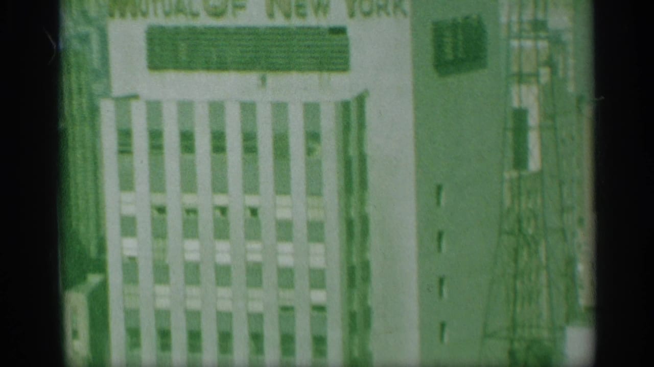 1959 New York frame with the Mutual of New York sign partly visible above a vertical-window office facade and adjacent rooftop structure.