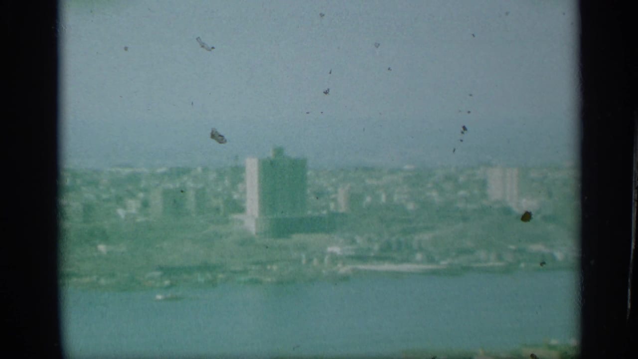 1959 New York aerial footage appears to show waterfront buildings across a wide river, with a tall rectangular tower in the distance.