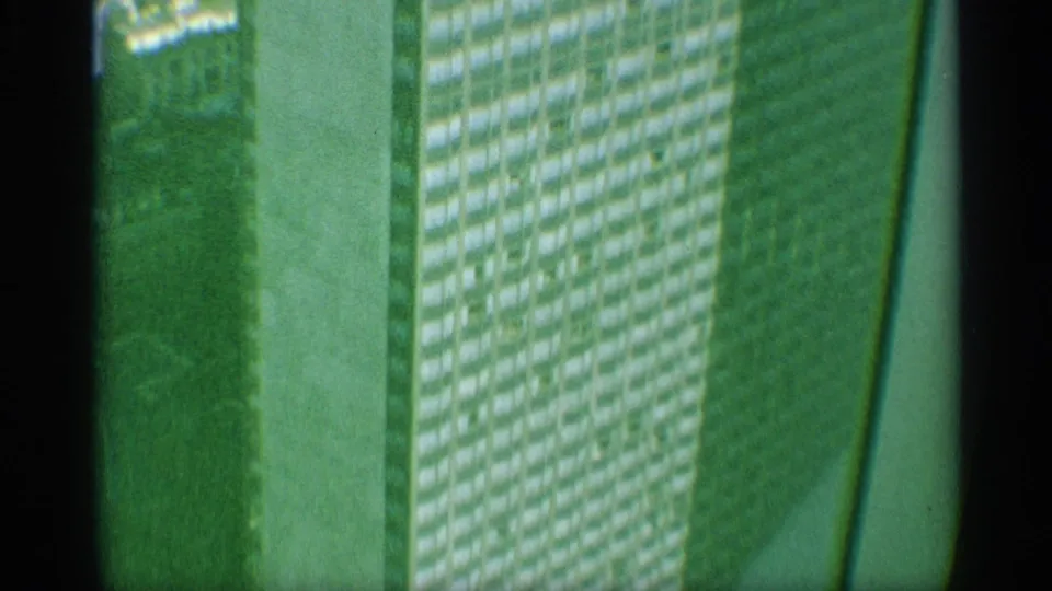 Green-tinted 1959 New York 8mm view of a high-rise facade, showing repeated window rows, a pale structural band, and dark film-edge framing.