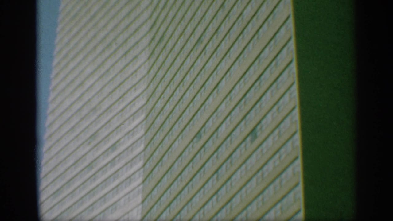 Close upward view of a gridded office tower facade beside a dark vertical edge.