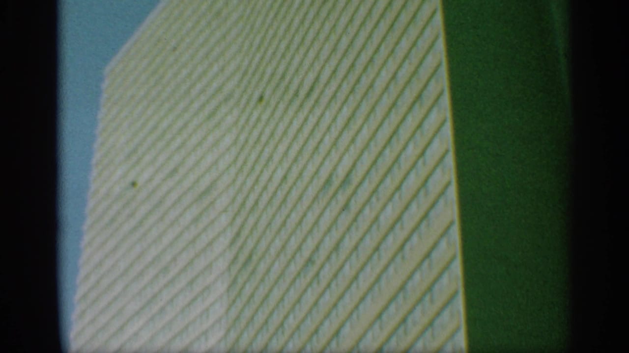 1959 New York 8mm frame of the tower facade rising diagonally across the view, with visible grain and greenish tint.