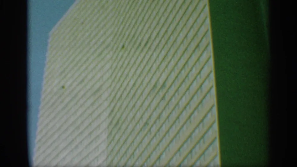 1959 New York 8mm frame of the tower facade rising diagonally across the view, with visible grain and greenish tint.