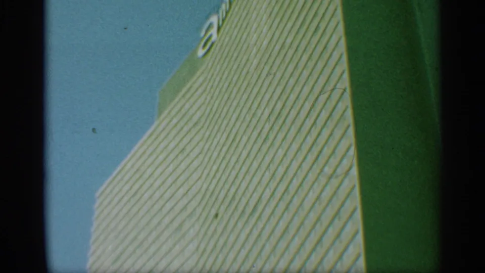 1959 New York frame showing the high-rise corner, gridded windows, blue sky, and partial unidentified lettering near the roofline.