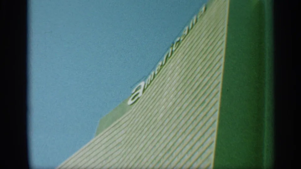 1959 New York 8mm frame showing the striped skyscraper facade from below, with partial letters along the upper edge.