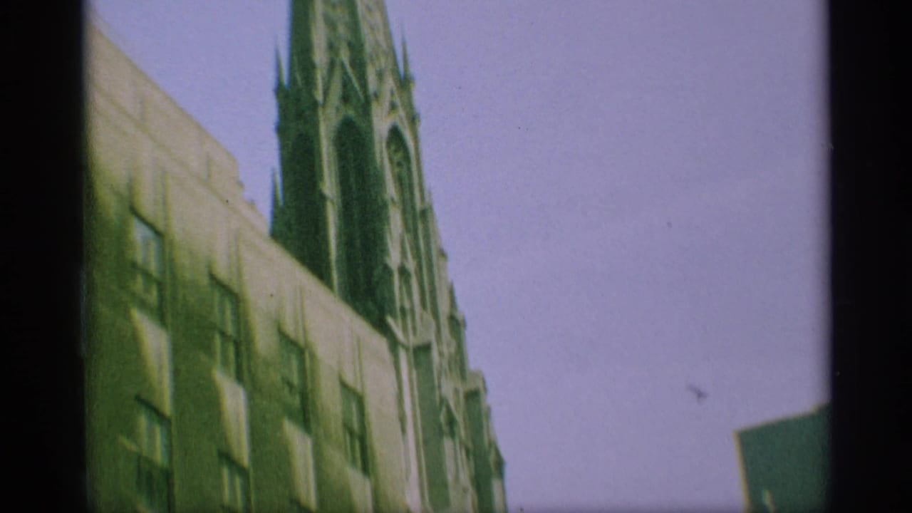 1959 New York 8mm frame looking up along the cathedral wall toward a narrow Gothic spire.