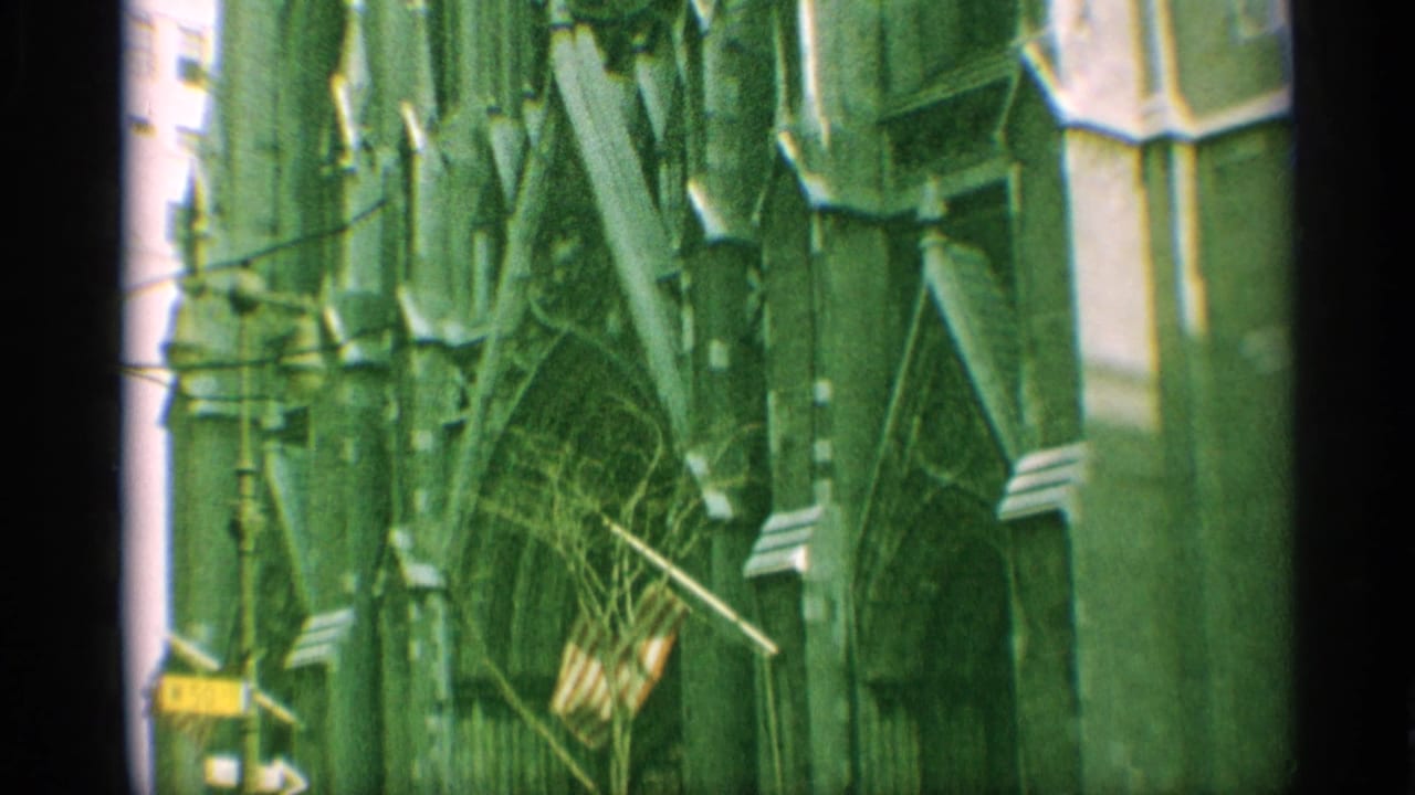1959 New York 8mm frame showing Gothic entrance details, stone arches, and an American flag near the cathedral facade.