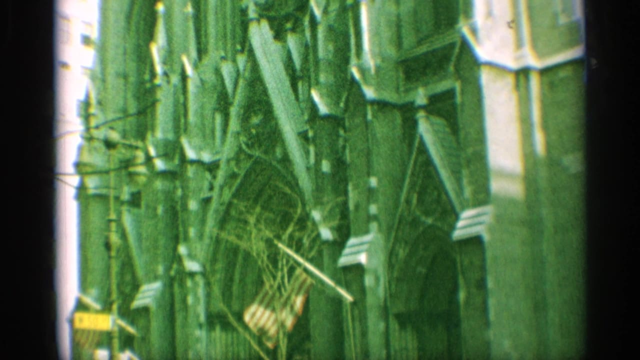 1959 New York 8mm frame showing ornate Gothic church architecture along a narrow city street, with flags below and strong green film tint.