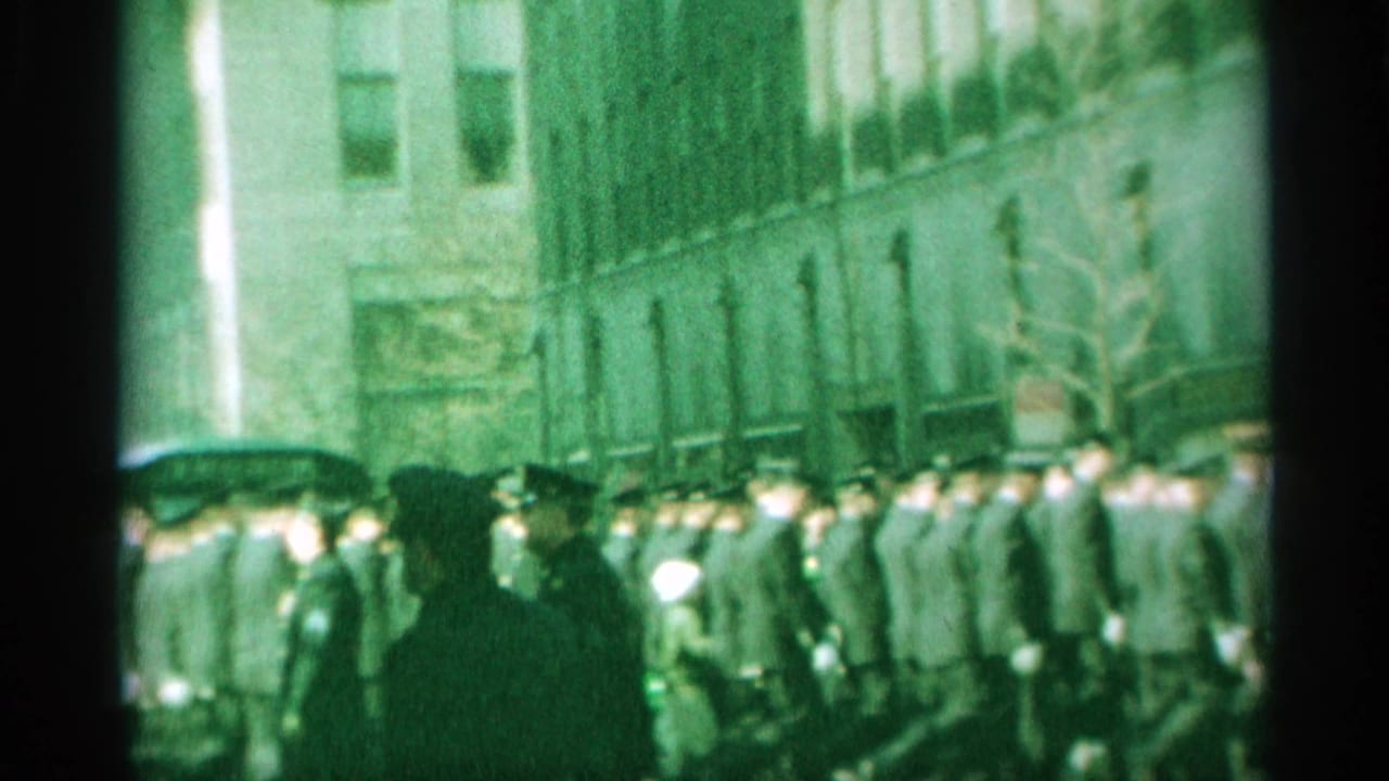 The final 1959 New York frame looks down a busy street as uniformed men continue past storefronts and pedestrians under tall building facades.