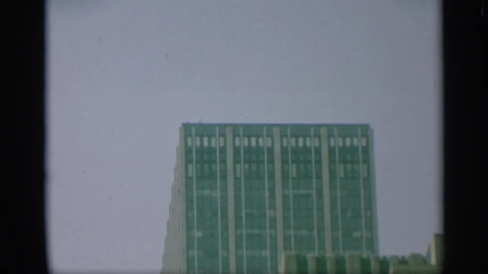 1959 New York 8mm frame with the top of a rectangular high-rise set low in the frame beneath a large pale sky.