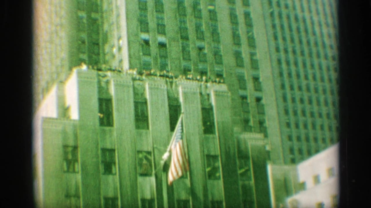 Tall New York building facade with an American flag and nearby skyscrapers.