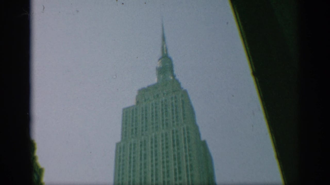 Empire State Building upper section and spire framed by dark film edges.
