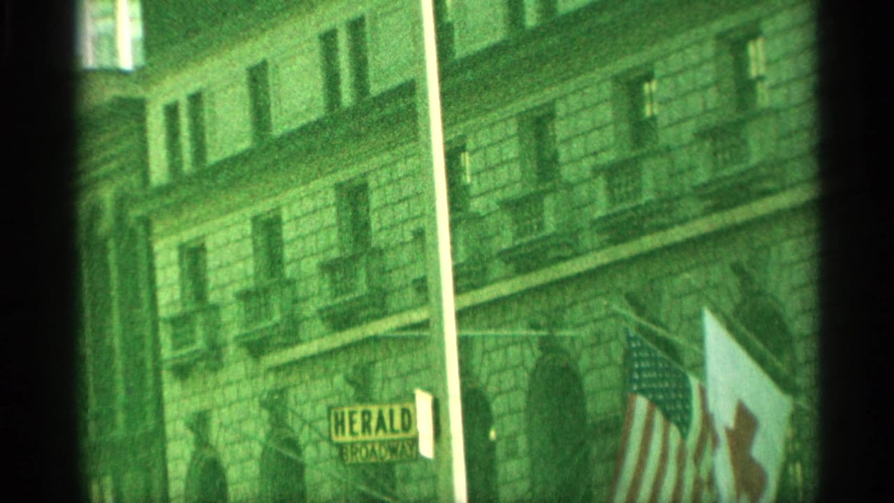 1959 New York street view near Macy's showing building facades, flags, a fire escape, and a Herald Square sign.