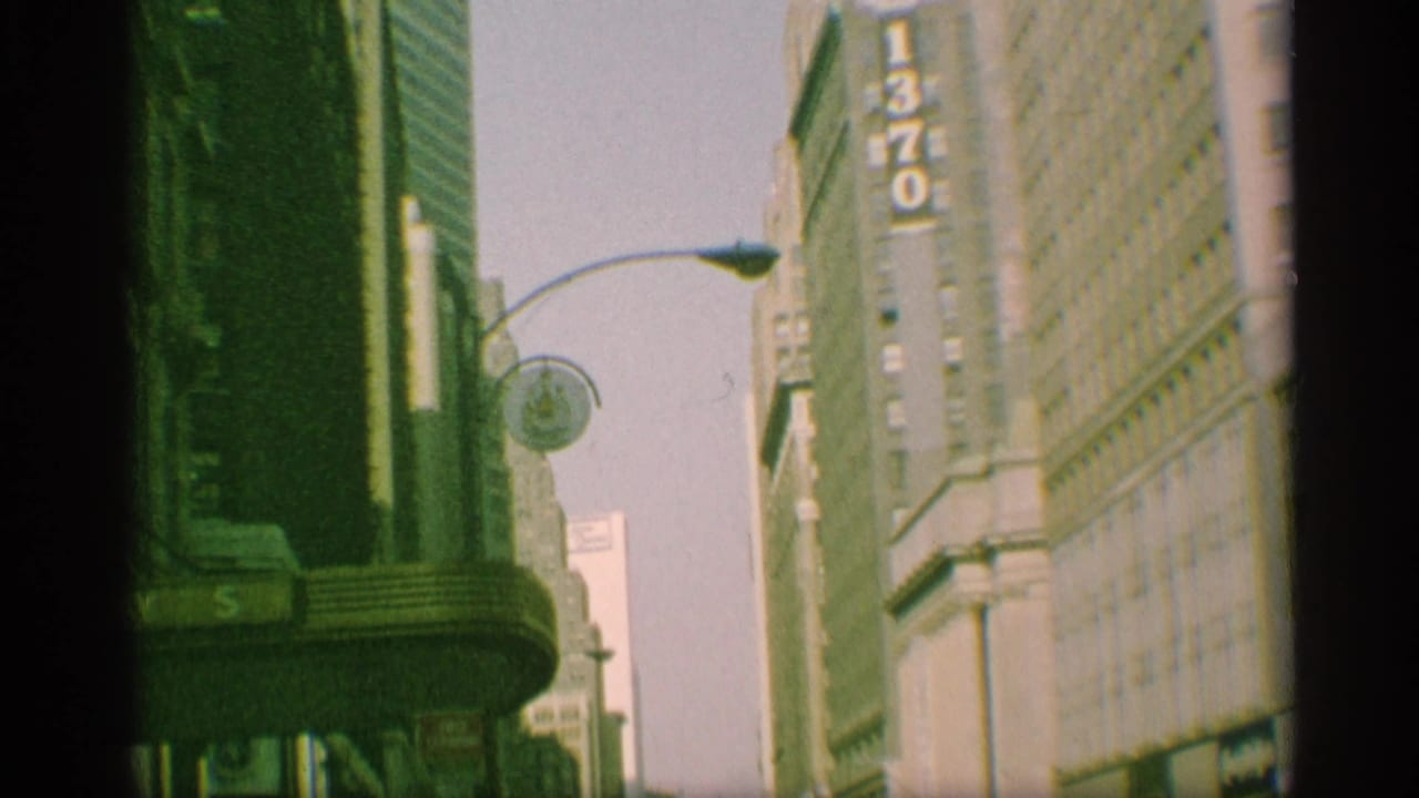 Tall city buildings with a vertical 1370 sign, street lamp, and flag partially visible.