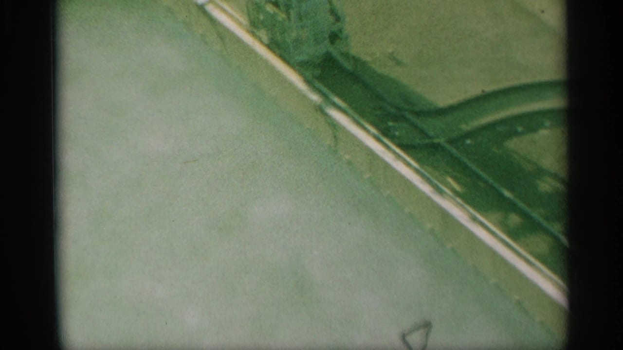Close elevated view of a pale water surface and dark building reflection or shadow in 1959 New York footage.
