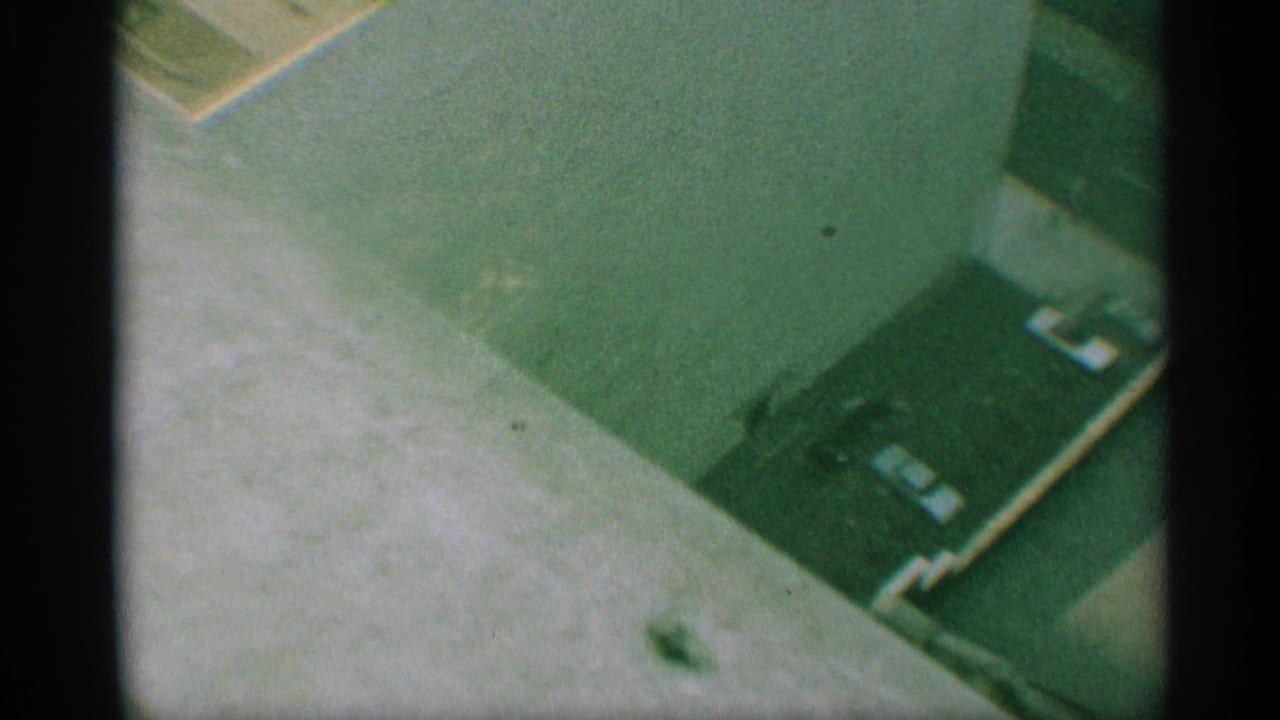 Downward view of a rooftop parking area with several parked cars and building edges.
