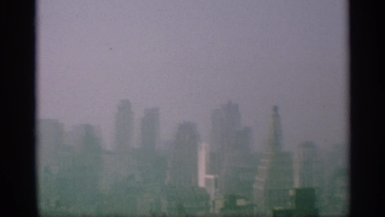Late-1950s New York skyline view with softened high-rises and a tall rooftop or column-like structure visible at the right edge.