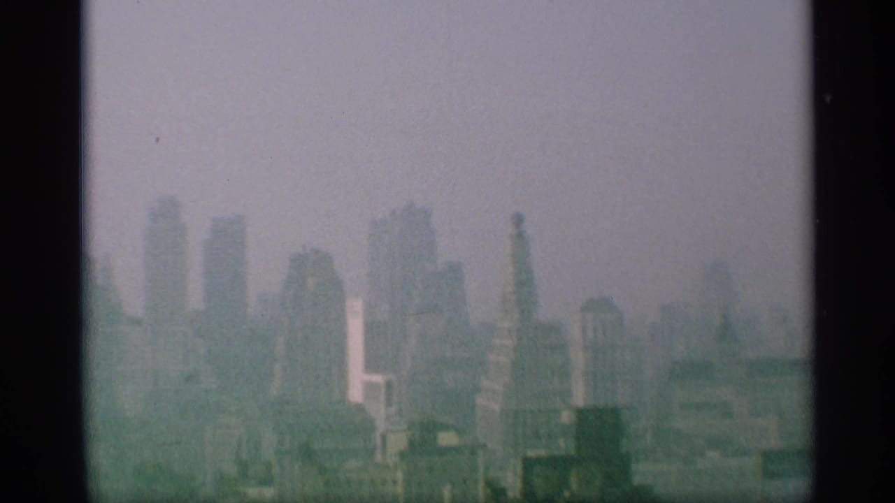 1959 New York skyline appears through haze, with distant skyscrapers and dark window-like edges in the foreground.