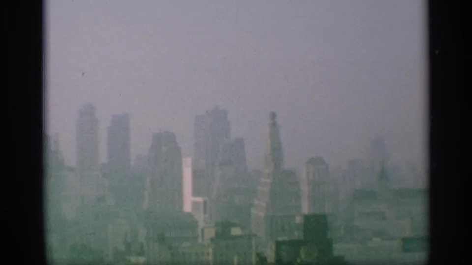 1959 New York skyline appears through haze, with distant skyscrapers and dark window-like edges in the foreground.