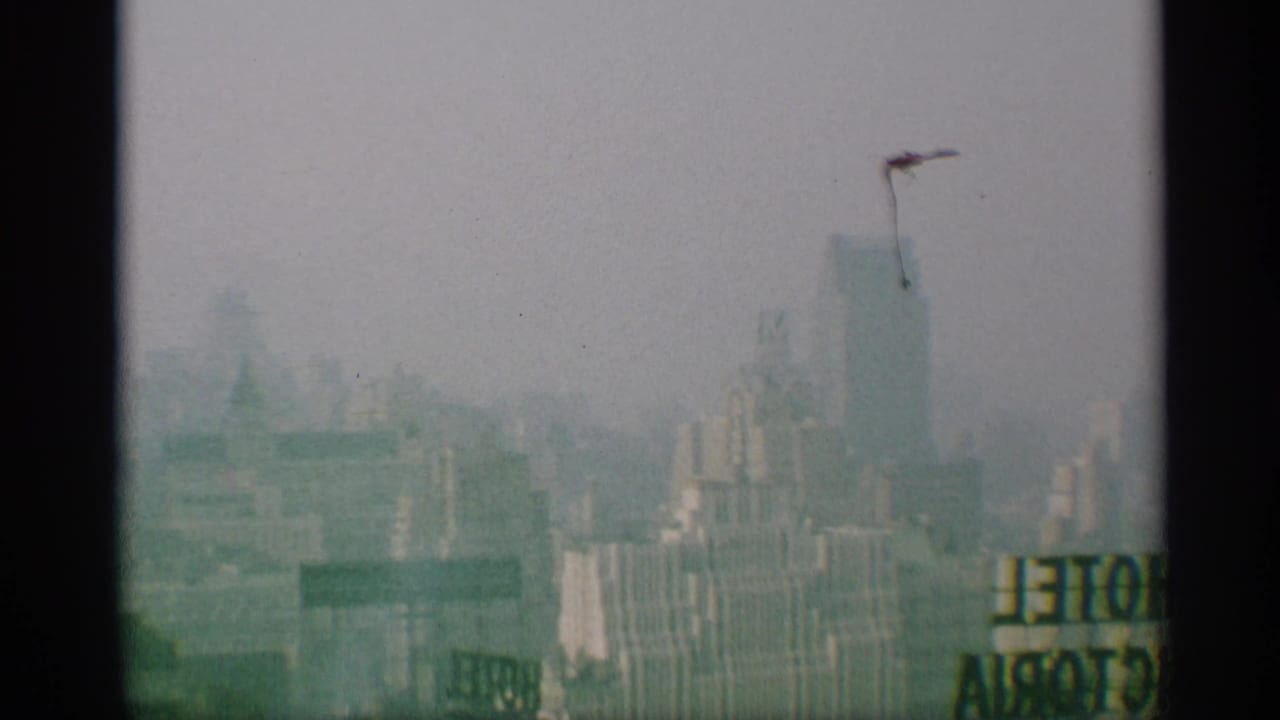 A mid-century New York skyline view includes a partial sign near the lower edge and a tall blocky building in haze.