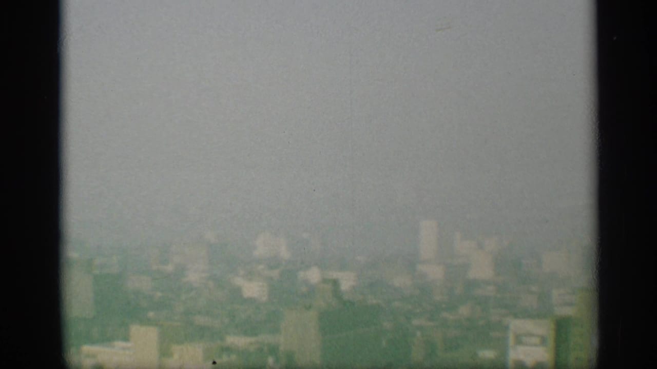 1959 New York skyline appears hazy and distant, framed by dark vertical bars in an elevated 8mm view.