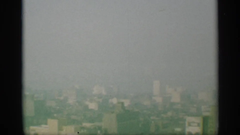 1959 New York skyline appears hazy and distant, framed by dark vertical bars in an elevated 8mm view.
