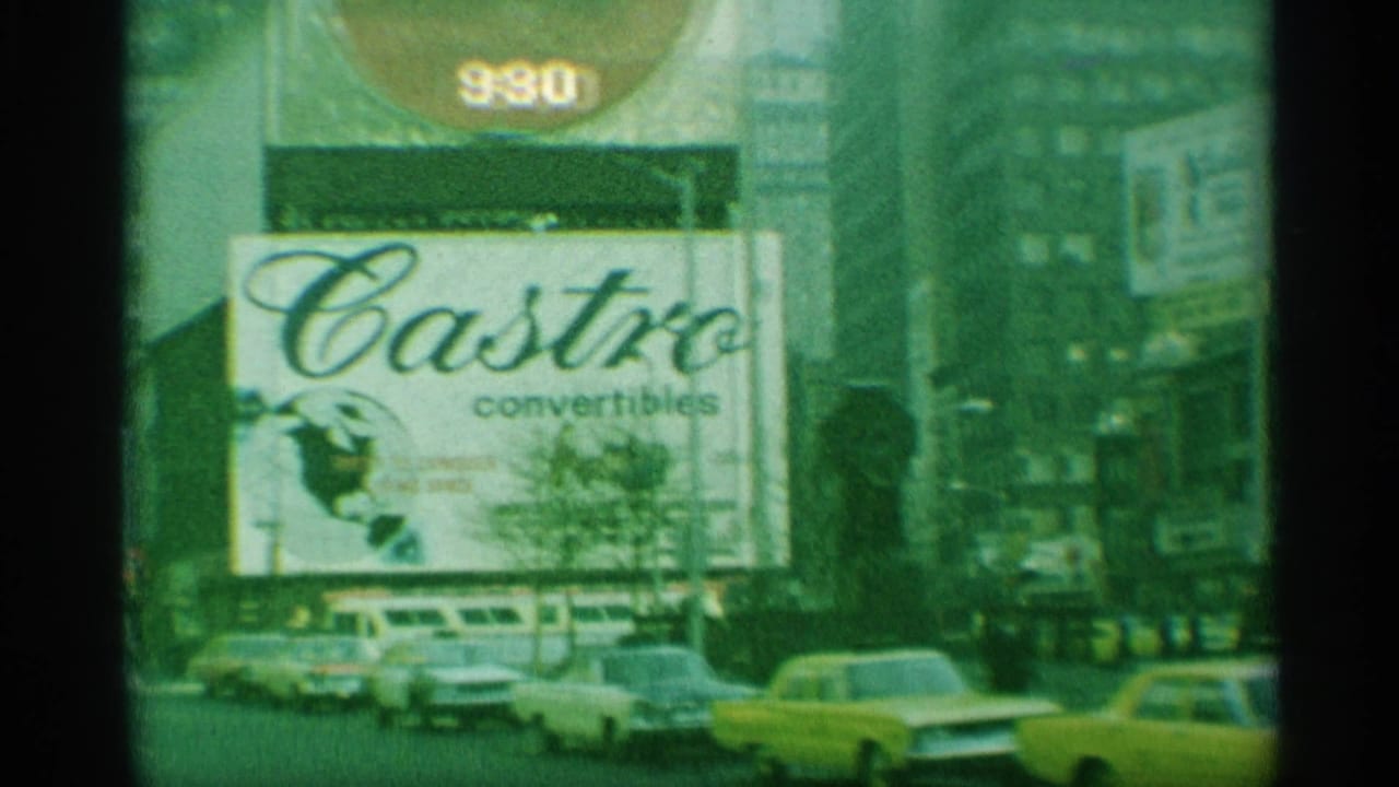 1959 New York street view with a Castor Convertibles billboard above taxis, parked cars, and tall city buildings.