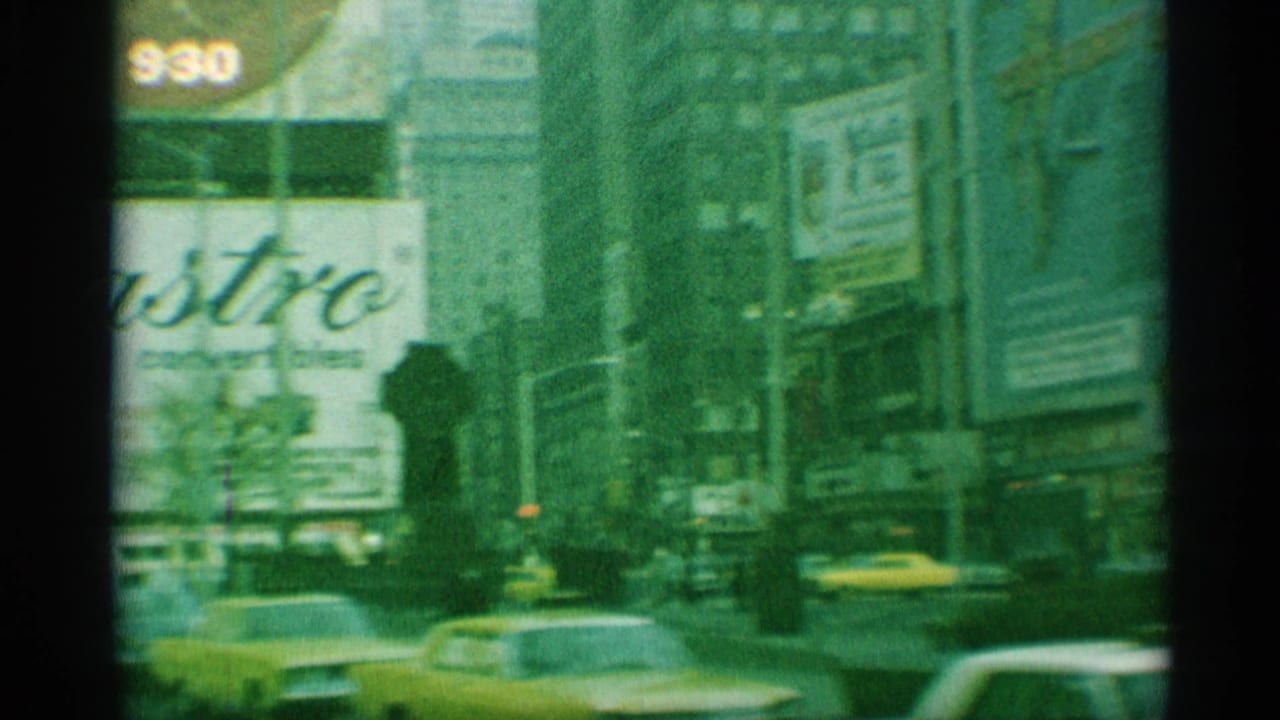 Busy city street with yellow cabs, classic cars, tall buildings, and large billboards.