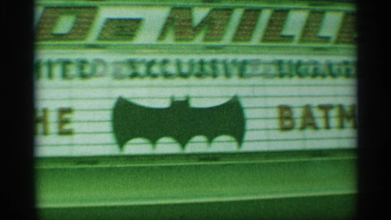 Close view of a New York theater marquee with a large bat symbol and partial lettering visible in 1959 8mm footage.