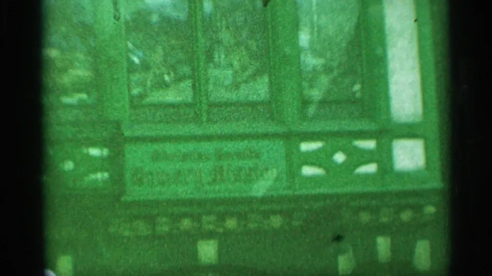 Handheld 1959 New York 8mm view of a theater entrance area with display cases, marquee details, and green color shift.