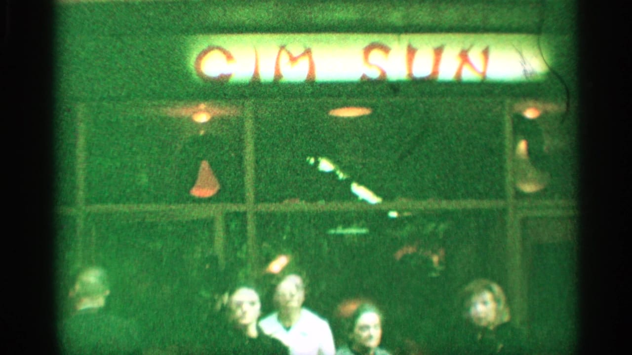 1959 New York street view with adults gathered below the red-letter Cim Sun sign and green storefront windows.