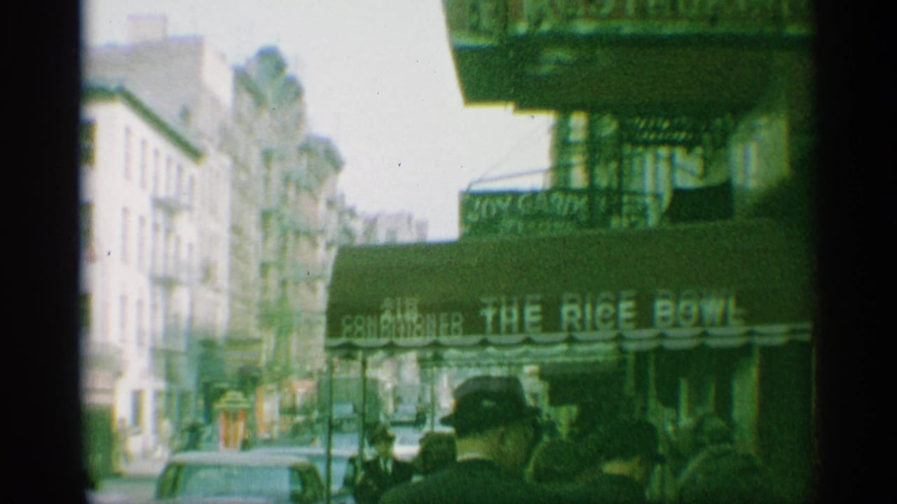 1959 New York sidewalk scene with pedestrians near the Rice Bowl restaurant awning and older cars in the street.
