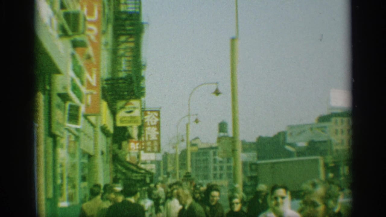 Crowded sidewalk with storefronts, Japanese signage, fire escapes, and pedestrians.