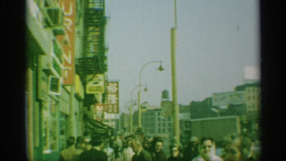 1959 New York street scene with pedestrians passing storefronts marked by Japanese-language signs and fire escapes above.