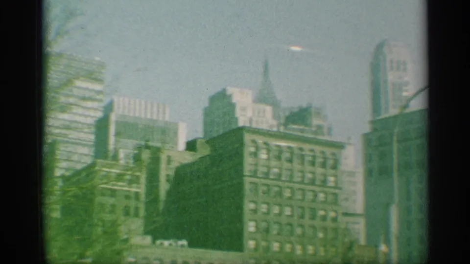 1959 New York skyline frame with office towers, older buildings, and a small bright elongated mark in the sky.